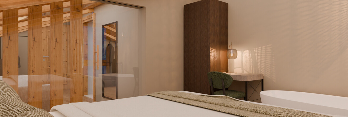 Schlafzimmer mit sichtbarer Holzbalkendecke, Doppelbett mit Kissen und Decke, freihstehende Badewanne, dunkler Schrank und grünem Stuhl vor weißer Wand.