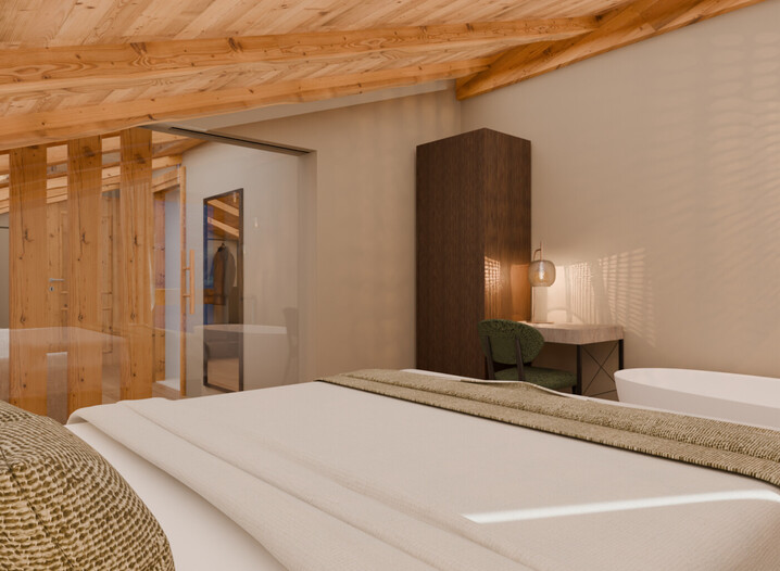 Schlafzimmer mit sichtbarer Holzbalkendecke, Doppelbett mit Kissen und Decke, freihstehende Badewanne, dunkler Schrank und grünem Stuhl vor weißer Wand.