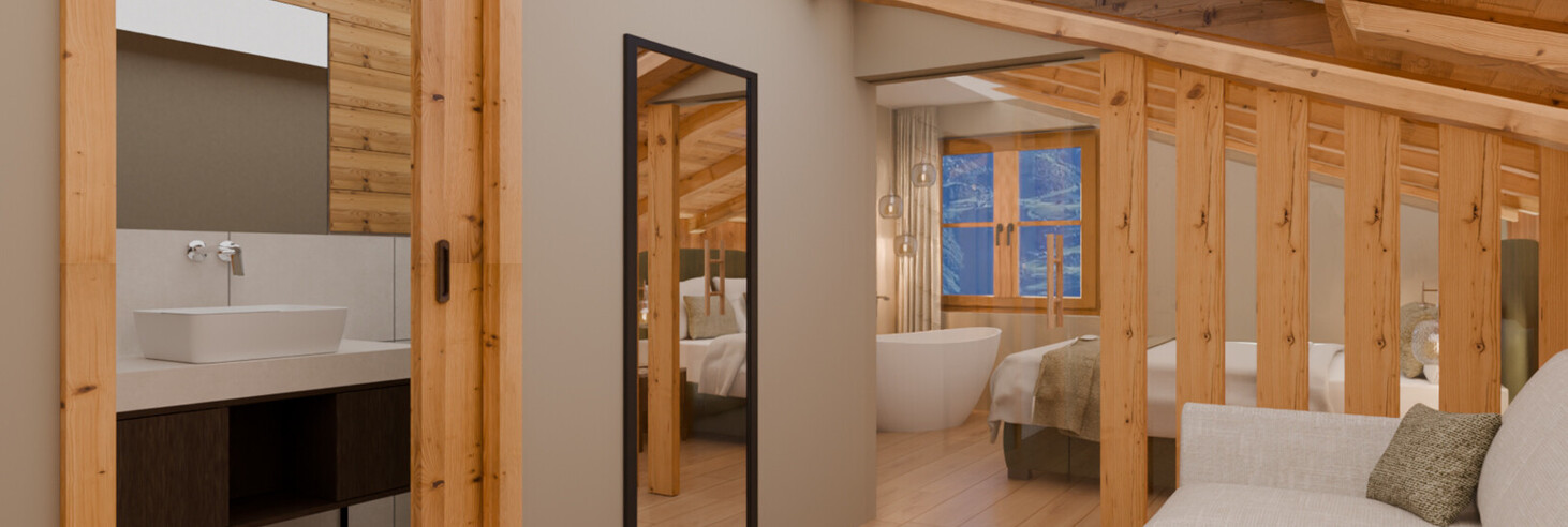 Zimmer mit Sofa, großem Spiegel, Holzbalkendecke und Blick in ein Badezimmer mit Waschbecken und in ein Schlafzimmer mit freistehender Badewanne.