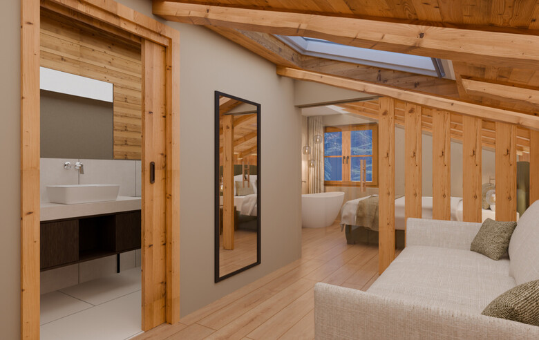 Zimmer mit Sofa, großem Spiegel, Holzbalkendecke und Blick in ein Badezimmer mit Waschbecken und in ein Schlafzimmer mit freistehender Badewanne.